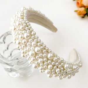 Detailed close-up of a wide Baroque headband with white pearls on light fabric