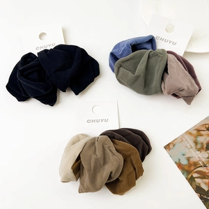 Detail of soft wide fabric hair ties in earthy tones on a white display card