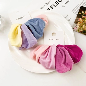 Detail view of colorful wide fabric hair scrunchies on white display card packaging