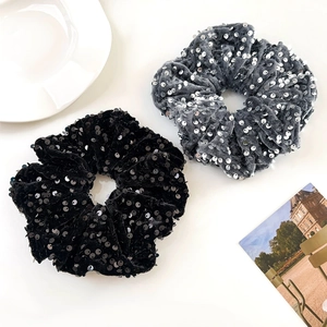 Detail of black and gray velvet scrunchies with shiny silver sequins on white surface