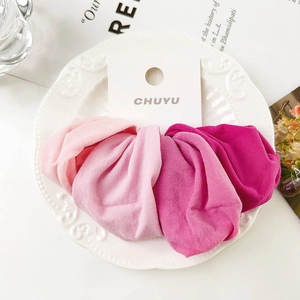 Close-up of four soft pink fabric scrunchies arranged on a decorative white plate