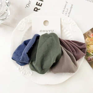 Detail of four colorful soft ribbed hair ties on display card inside a ceramic plate