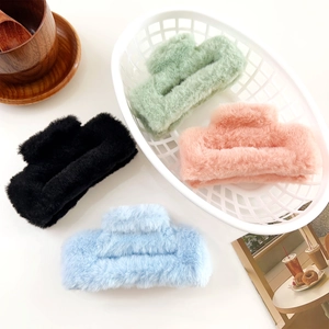 Detail showing four plush faux fur hair claw clips in black, green, pink and blue colors