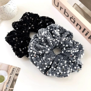 Macro detail of large velvet scrunchies with shiny sequins in black and grey colors