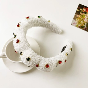 Detail of white fluffy headband with colorful gems on a ceramic cup and saucer