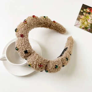 Detail of plush khaki headband with colorful gems next to a white coffee cup