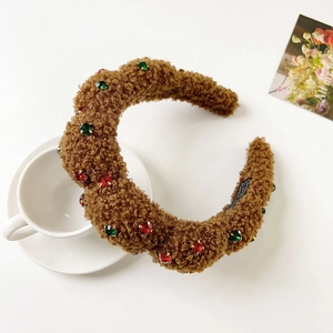 Detail of brown faux fur headband with red and green gemstone accents for winter