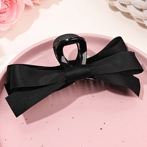 Gros plan détaillé de la grande pince à cheveux en satin noir sur assiette rose
