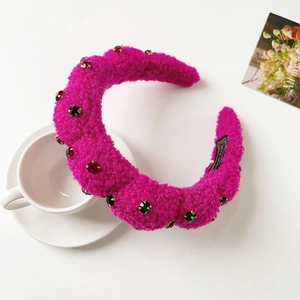 Detailed close-up of rose red plush headband with colorful gems and hand made label