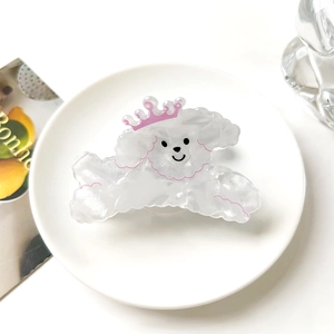 Detalle de pinza para el pelo de caniche con corona rosa en plato de cerámica blanco