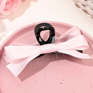 Détail de la pince à cheveux à nœud en satin rose avec tissu double épaisseur élégant