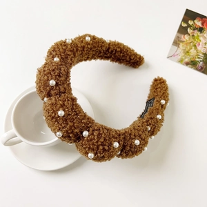 Close-up of warm brown plush headband with white pearls and twisted fuzzy fabric texture