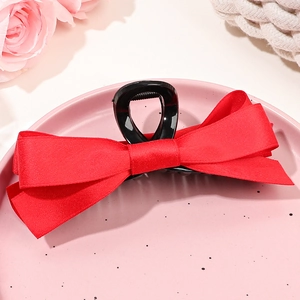 Grande pince à cheveux avec nœud en satin rouge sur une assiette décorative
