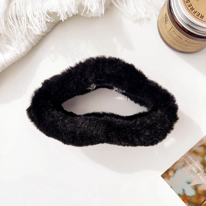 Detail of premium black plush hair claw clip on warm aesthetic home decor background
