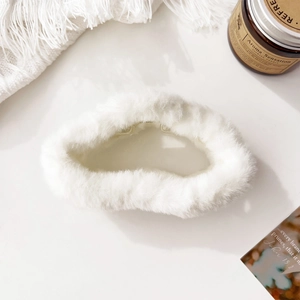Detail of soft white plush claw clip on a cozy white knitted blanket background
