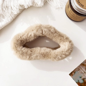 Macro detail of a large fluffy brown cloud hair claw clip on a warm cozy background