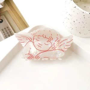 Vue détaillée de la pince à cheveux ange nacrée avec motif cupidon rouge élégant
