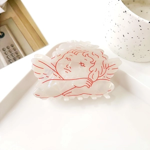 Détail de la pince à cheveux ange avec fini nacré et motif aux contours rouges fins
