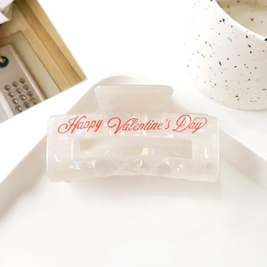Gros plan sur la pince à cheveux blanc perle avec texte Happy Valentine's Day rouge