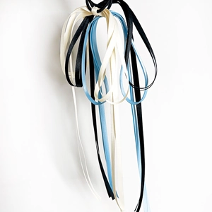 Détail de chouchous en ruban de satin crème, noir et bleu clair à texture lisse