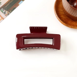 Détail d'une pince à cheveux rectangulaire rouge foncé brillante au design ajouré