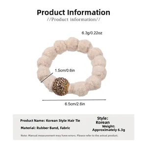 Detail of plush beige hair scrunchie with sparkling brown rhinestone ball and soft wavy texture