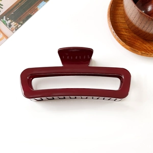 Détail macro de la pince à cheveux rectangulaire rouge foncé sur fond blanc uni