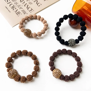 Close-up of four knitted elastic hair ties with sparkling rhinestone beads in earthy tones