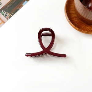 Détail d'une grande pince à cheveux rouge foncé brillante avec un design torsadé en résine