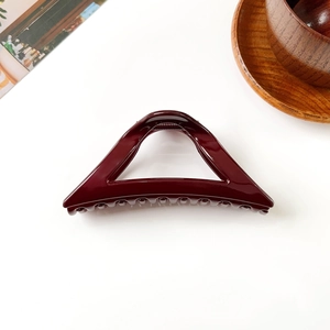 Vue détaillée de la grande pince à cheveux triangle rouge foncé avec finition polie