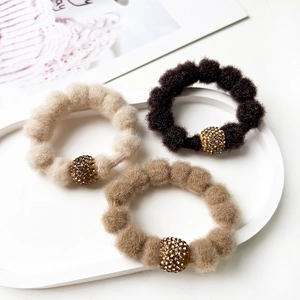 Close-up of three plush elastic hair ties with sparkling rhinestone beads in earthy tones