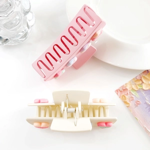 Détail de pinces à cheveux mates rose et crème avec fleurs 3D sur un plateau blanc