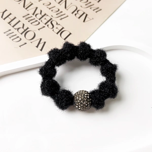 Detailed shot of black plush hair scrunchie with sparkling pavé crystal ball ornament