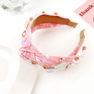 Détail du serre-tête en tissu rose avec perles en cœur et cristaux pour la Saint-Valentin