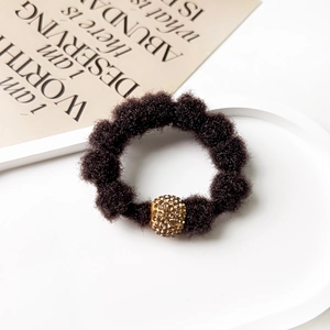 Detail of dark brown plush scrunchie with sparkling gold rhinestone bead on a display plate