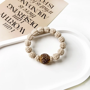 Detailed close-up of beige woven beads with a sparkling brown rhinestone center on the band