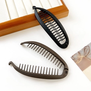Close-up of matte banana hair clips in black and coffee brown on a wooden display