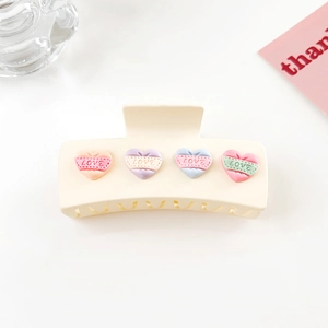 Gros plan sur la pince à cheveux crème avec cœurs LOVE colorés sur fond blanc