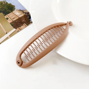 Close-up of matte mocha banana hair clip on a white ceramic plate with a vintage card