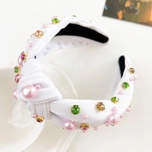 Detail eines weißen Knotenstirnbands mit rosa Perlen und bunten Strasssteinen