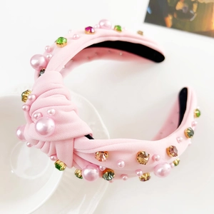 Detail eines rosa geknoteten Haarreifens mit bunten Strasssteinen und Kunstperlen