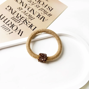Close-up of woven brown hair scrunchie with sparkling rhinestone square buckle detail
