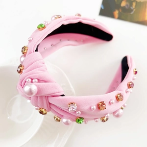 Detailansicht eines rosa Knotenstirnbands mit bunten Kristallen und glänzenden Perlen