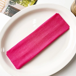 Detail of rose red knitted yoga headband with elastic ribbed texture on a white tray