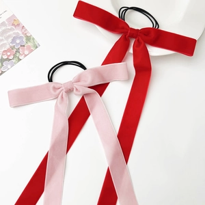Close-up of velvet bow hair ties with long ribbons in red and pink colors