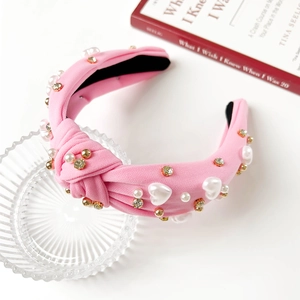 Detailansicht eines rosa Stoffstirnbands mit Herzperlen und künstlichen Perlenverzierungen