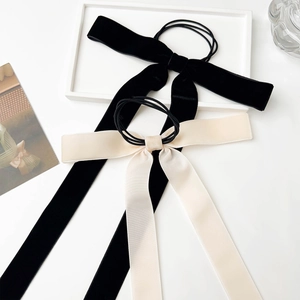 Close-up of black and cream velvet bow hair ties with long flowing ribbons on a tray