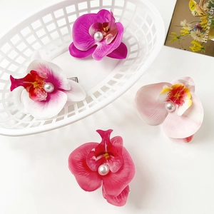 Detailed macro shot of floral orchid hair clips with pearls on a decorative white basket