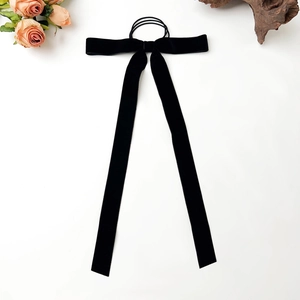 Detailed close-up of a black velvet ribbon bow hair tie with long hanging streamers