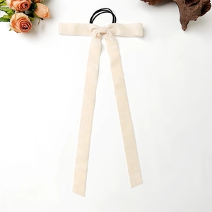 Detail view of cream white velvet bow hair tie with long ribbons on a white background